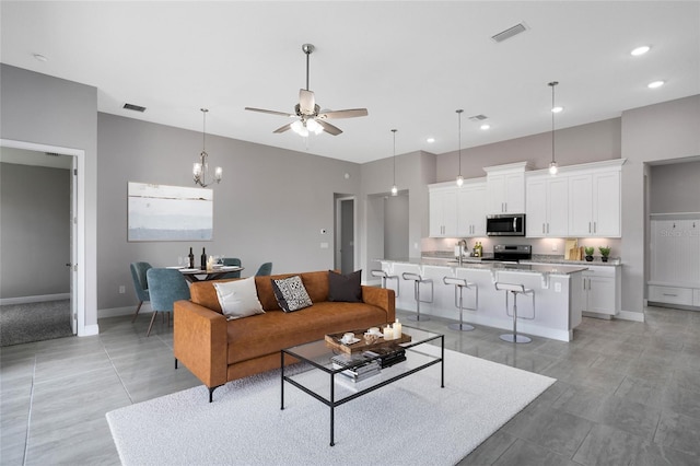 living area with ceiling fan with notable chandelier, recessed lighting, baseboards, and visible vents