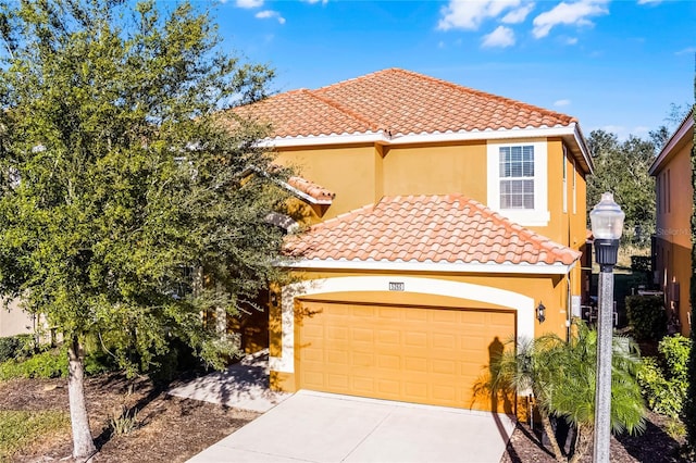 mediterranean / spanish house featuring a tile roof, concrete driveway, a garage, and stucco siding