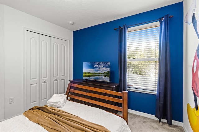 bedroom featuring a closet, a textured ceiling, baseboards, and carpet floors