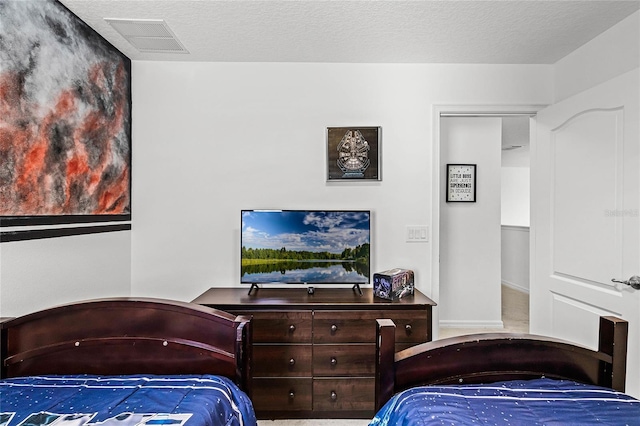 bedroom with visible vents, carpet flooring, and a textured ceiling