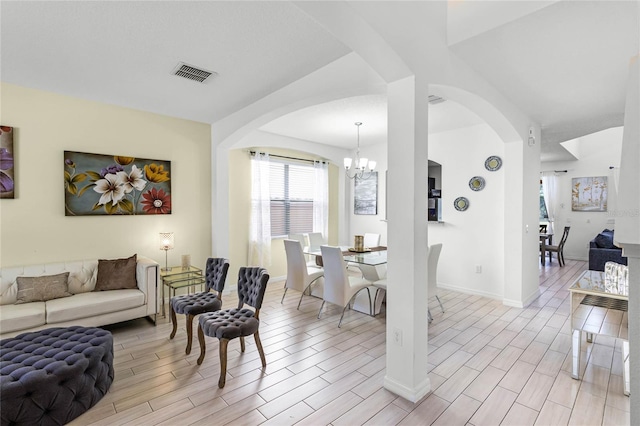 living room featuring a notable chandelier, visible vents, baseboards, and wood tiled floor