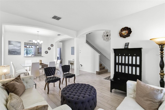 living area with stairway, a notable chandelier, arched walkways, and wood finish floors