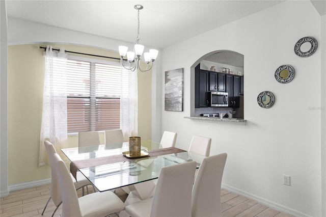 dining room with a chandelier, baseboards, and wood tiled floor