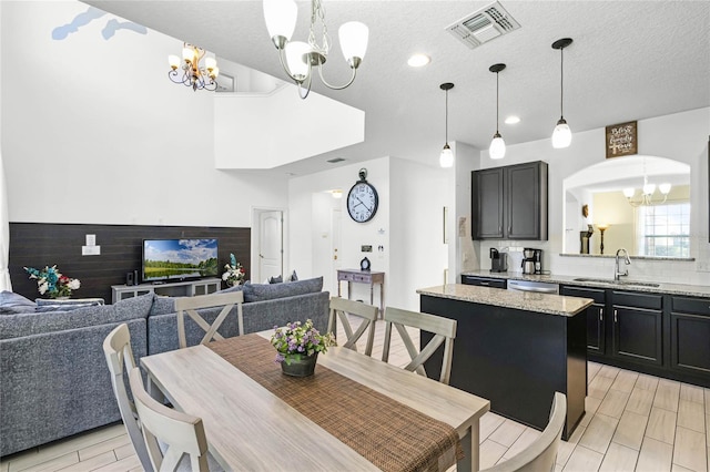 dining room featuring wood finish floors, visible vents, a notable chandelier, and a textured ceiling