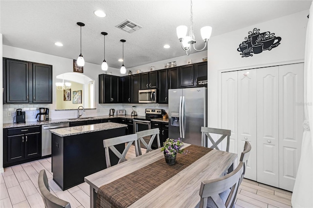 kitchen featuring an inviting chandelier, dark cabinetry, visible vents, and stainless steel appliances