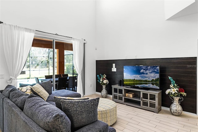 living area featuring baseboards, a towering ceiling, and wood finished floors