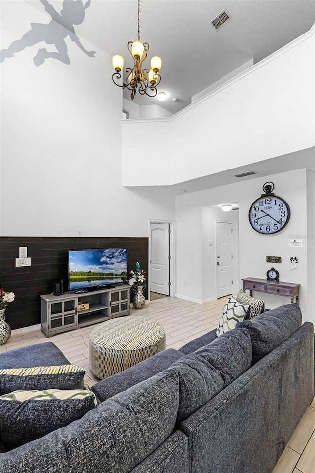 living room with wooden walls, wood finished floors, a wainscoted wall, visible vents, and a chandelier