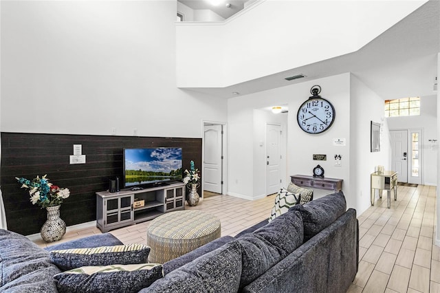 living area with wood finish floors, visible vents, a high ceiling, and wooden walls