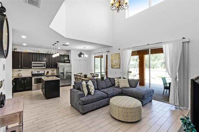 living room featuring light wood-type flooring, visible vents, a notable chandelier, and recessed lighting