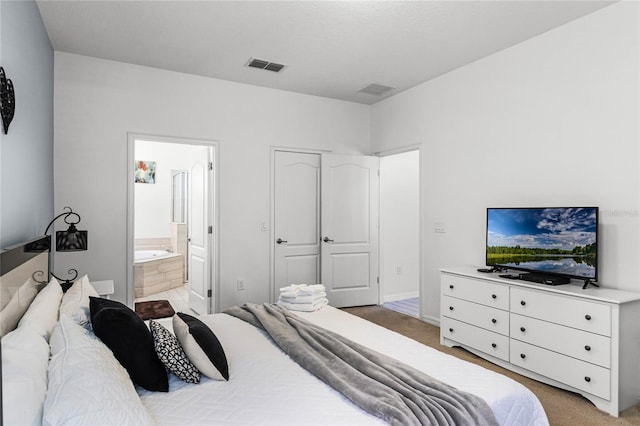 carpeted bedroom featuring visible vents and ensuite bathroom