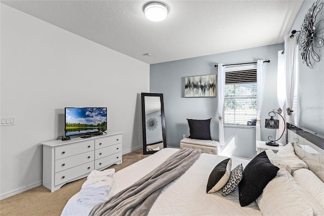 bedroom featuring light colored carpet, a textured ceiling, and baseboards