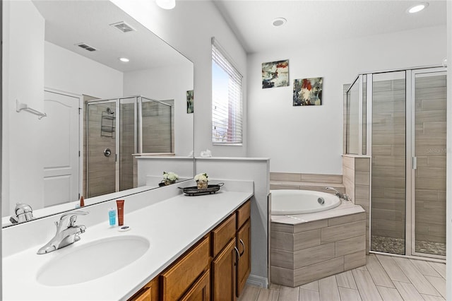 bathroom featuring visible vents, a shower stall, vanity, and a garden tub