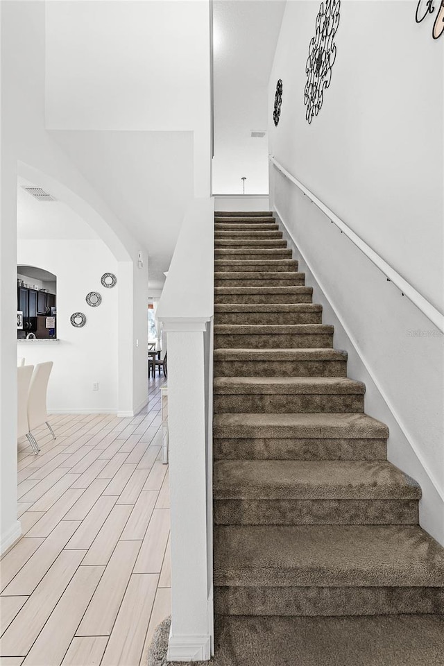 stairs featuring visible vents, arched walkways, and wood finished floors