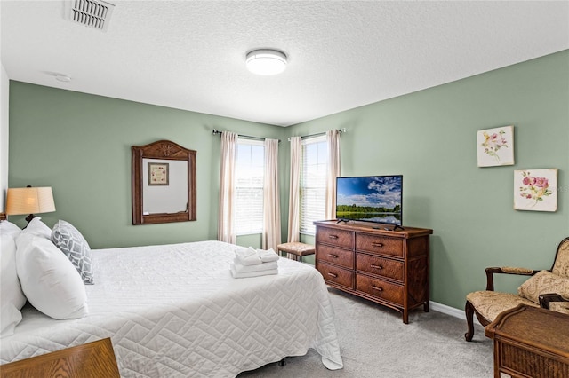 bedroom with visible vents, light colored carpet, a textured ceiling, and baseboards