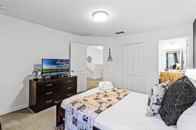 bedroom with baseboards, visible vents, a closet, a textured ceiling, and light carpet