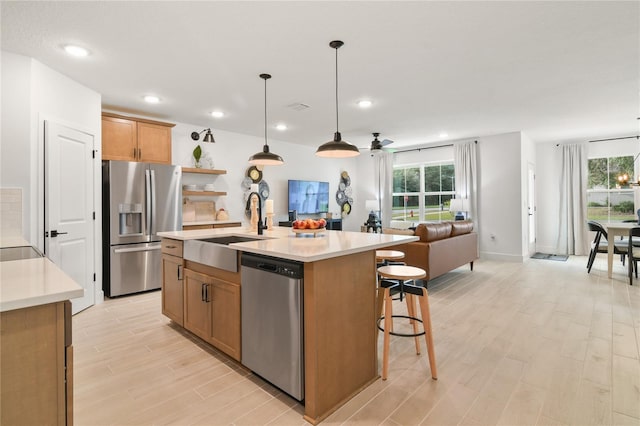 kitchen featuring a wealth of natural light, a sink, open floor plan, stainless steel appliances, and light countertops