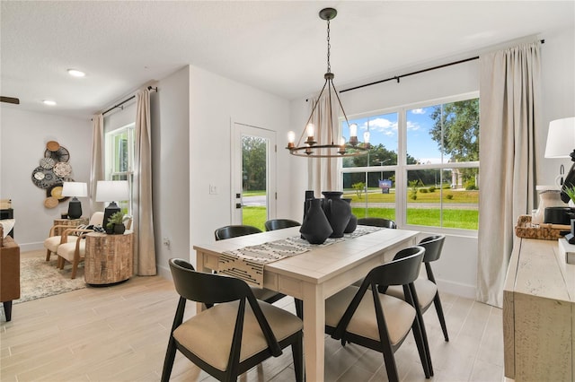 dining space featuring light wood finished floors, baseboards, recessed lighting, a notable chandelier, and a textured ceiling