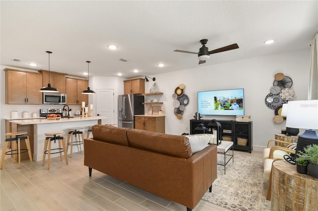 living room featuring light wood-type flooring, visible vents, recessed lighting, baseboards, and ceiling fan