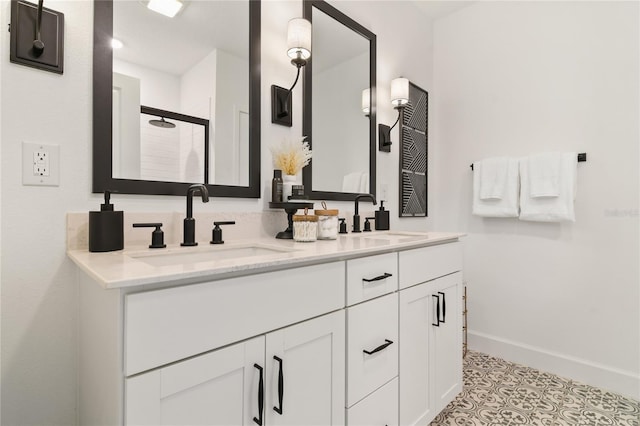 bathroom with a sink, baseboards, double vanity, and a shower stall