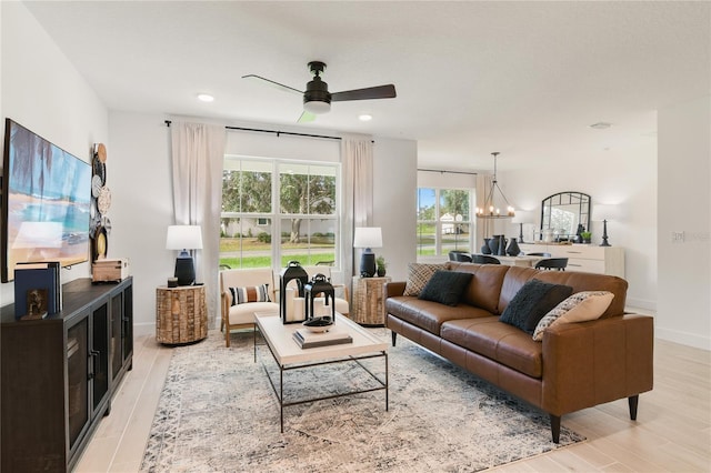 living room featuring recessed lighting, light wood-type flooring, baseboards, and ceiling fan with notable chandelier