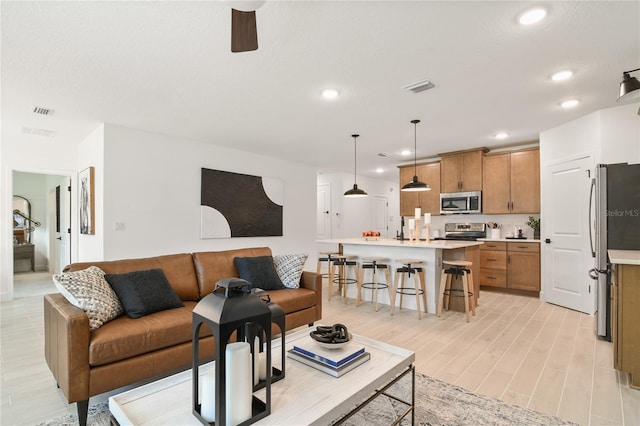 living area featuring recessed lighting, visible vents, and light wood-type flooring