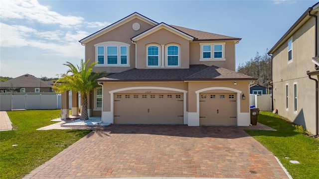 view of front of home featuring stucco siding, decorative driveway, a front lawn, and fence