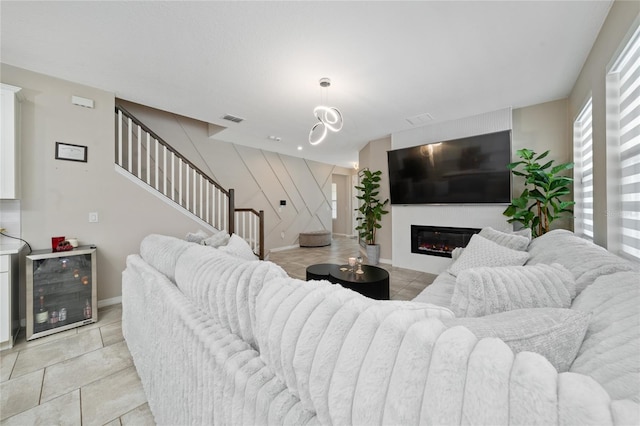 living room featuring visible vents, baseboards, stairs, light tile patterned floors, and a glass covered fireplace