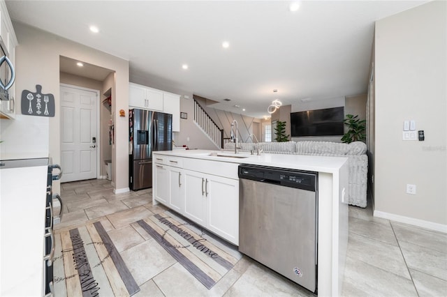 kitchen featuring a center island with sink, a sink, open floor plan, stainless steel appliances, and white cabinets