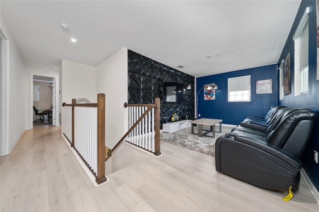 living room featuring an accent wall, baseboards, and wood finished floors