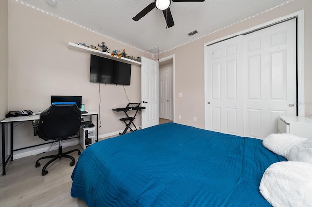 bedroom featuring visible vents, light wood-type flooring, a closet, a textured ceiling, and a ceiling fan