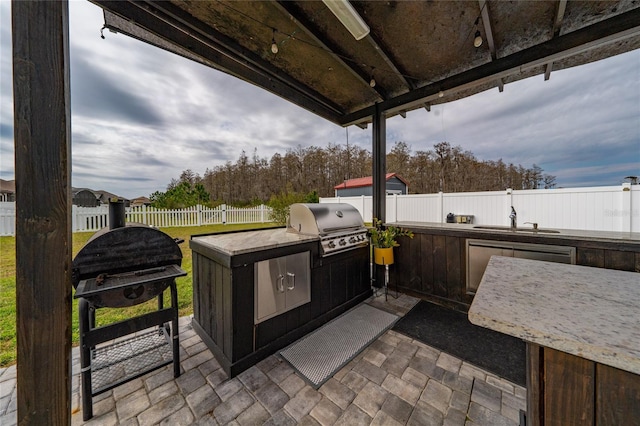 view of patio with a sink, exterior kitchen, a fenced backyard, and a grill