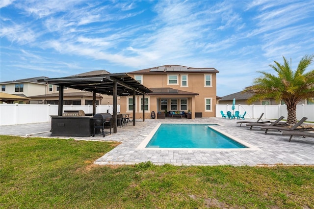 rear view of house featuring solar panels, a patio area, a fenced backyard, and a lawn