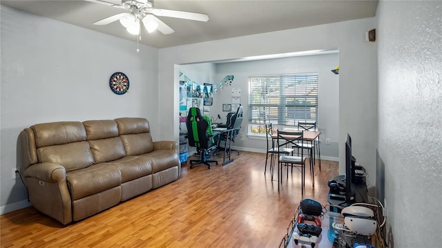 living room with light wood-style flooring, baseboards, and ceiling fan