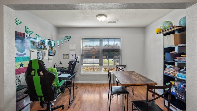 office with baseboards, wood finished floors, visible vents, and a textured ceiling