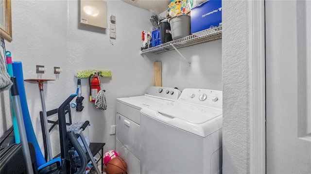 laundry area with a textured wall, laundry area, and washing machine and clothes dryer