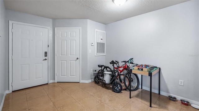 entryway featuring light tile patterned floors, baseboards, and a textured ceiling