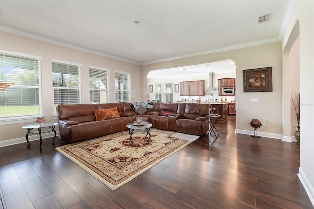 living room with visible vents, crown molding, dark wood-type flooring, baseboards, and arched walkways