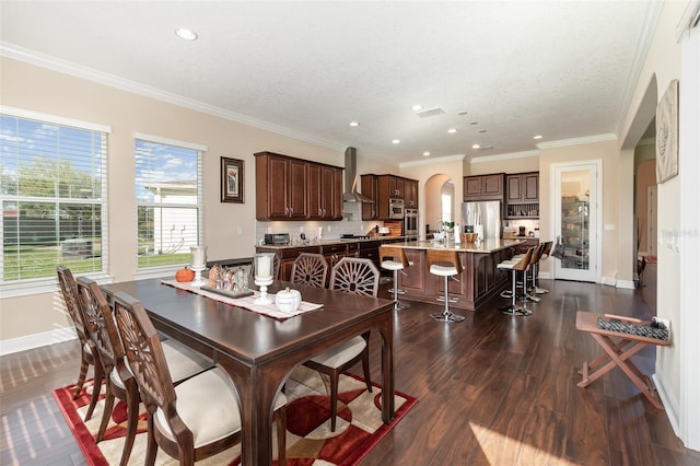 dining space featuring arched walkways, dark wood-style floors, crown molding, and baseboards