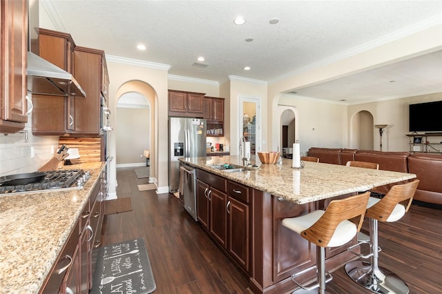 kitchen with light stone countertops, open floor plan, a kitchen bar, arched walkways, and dark wood-style flooring