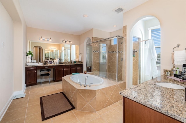 bathroom featuring visible vents, two vanities, a stall shower, a sink, and a bath