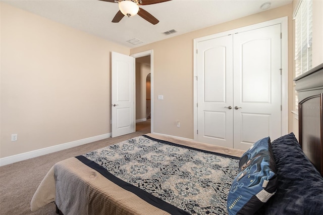 carpeted bedroom with visible vents, a closet, arched walkways, baseboards, and ceiling fan