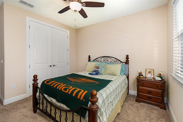 bedroom with visible vents, ceiling fan, baseboards, light carpet, and a closet