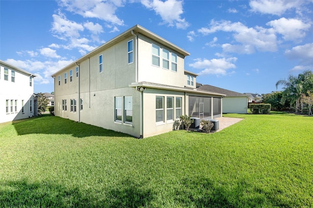 rear view of property with stucco siding, a lawn, central AC, and a sunroom