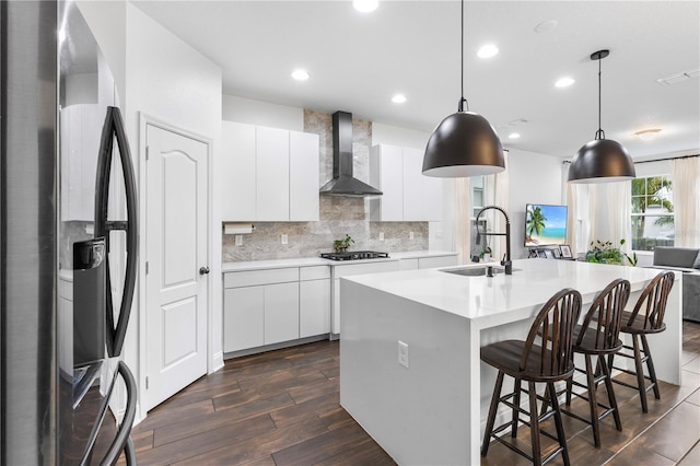 kitchen with a sink, tasteful backsplash, gas stovetop, stainless steel fridge with ice dispenser, and wall chimney range hood