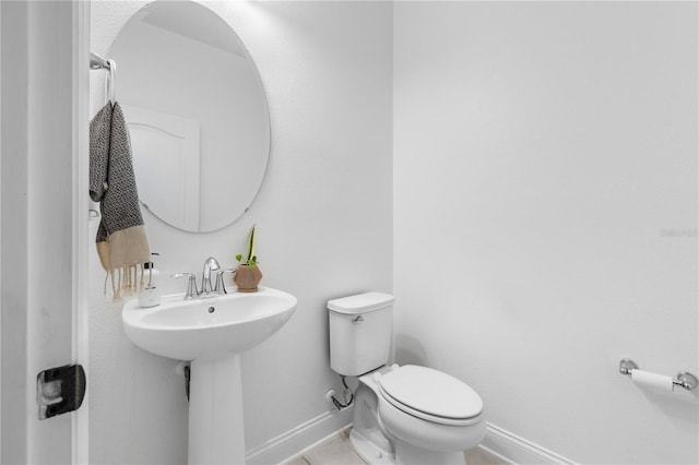 bathroom with toilet, baseboards, and a sink