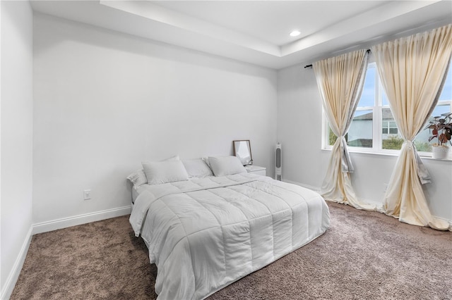 carpeted bedroom featuring recessed lighting, a tray ceiling, and baseboards
