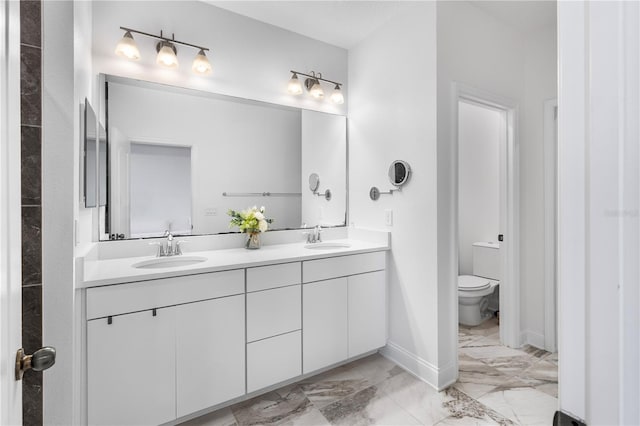 full bathroom featuring a sink, toilet, marble finish floor, and double vanity