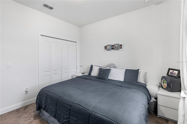bedroom with carpet, visible vents, baseboards, a closet, and a textured ceiling