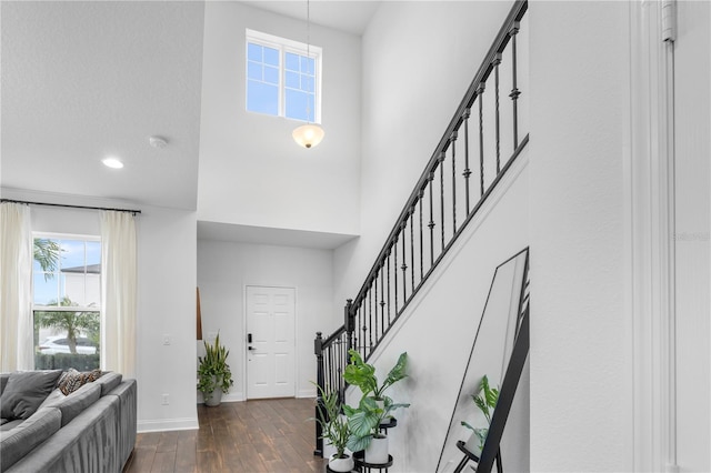 entrance foyer with dark wood finished floors, a high ceiling, stairs, and baseboards