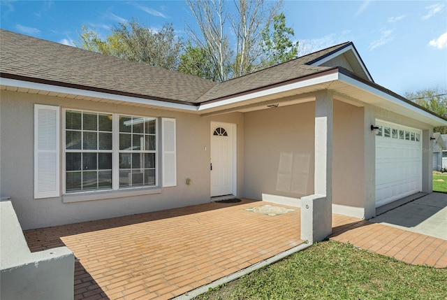 exterior space featuring stucco siding, a garage, and a shingled roof